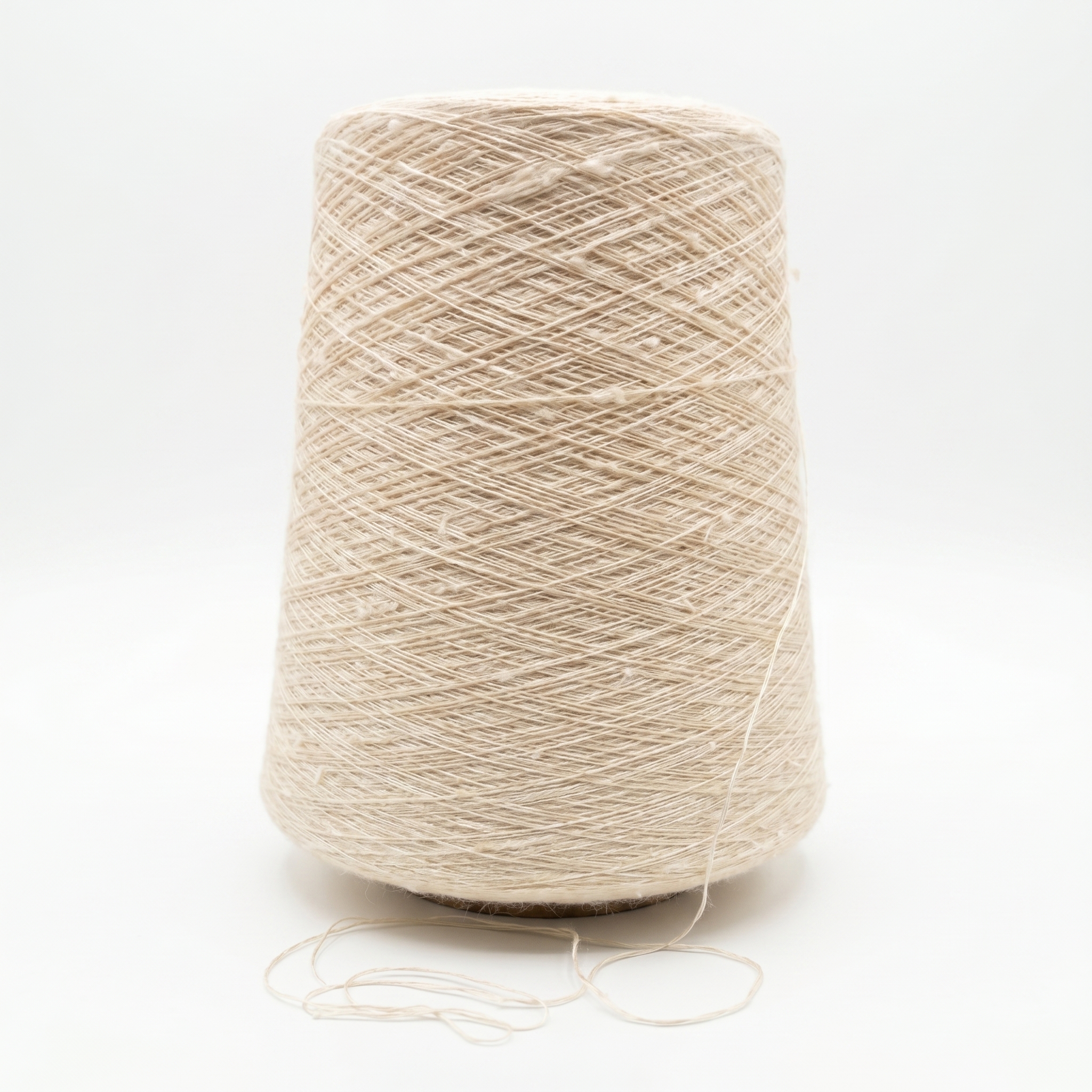 En stor cone av ljust beige, texturerat garn mot en vit bakgrund.