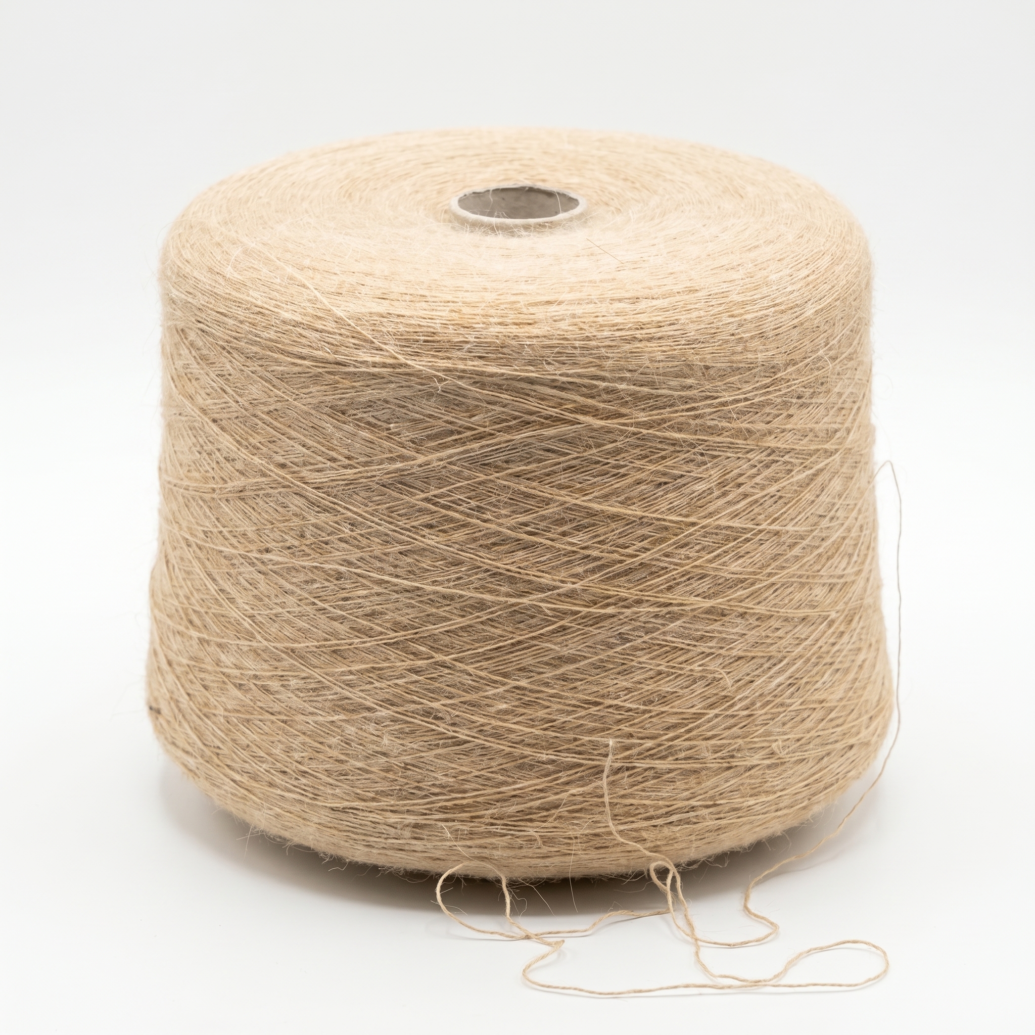 En stor cone med ljusbrunt, texturerat garn står på en vit yta, med några lösa trådar i botten.