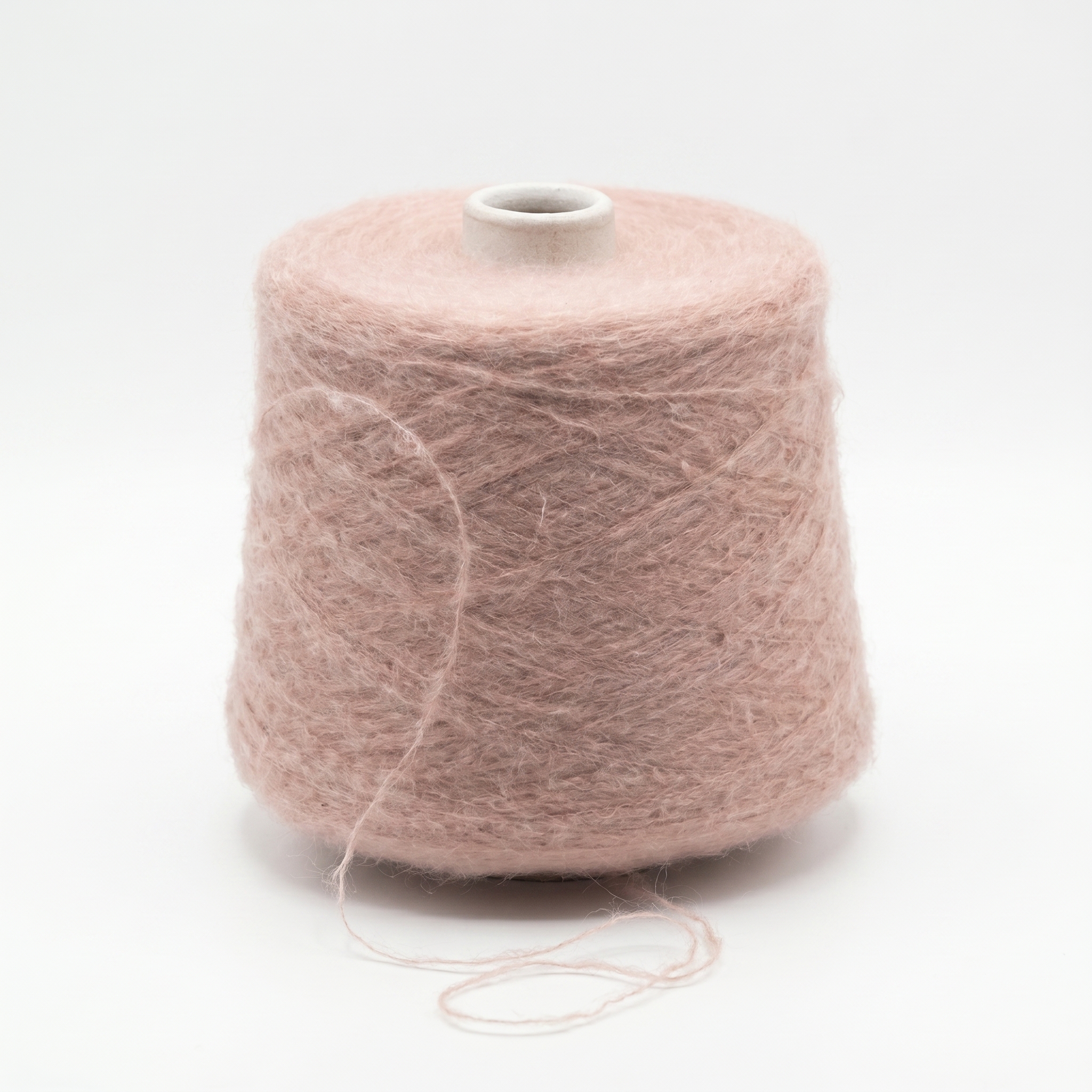 En cone med dammigt rosa, luddigt garn står på en vit bakgrund.
