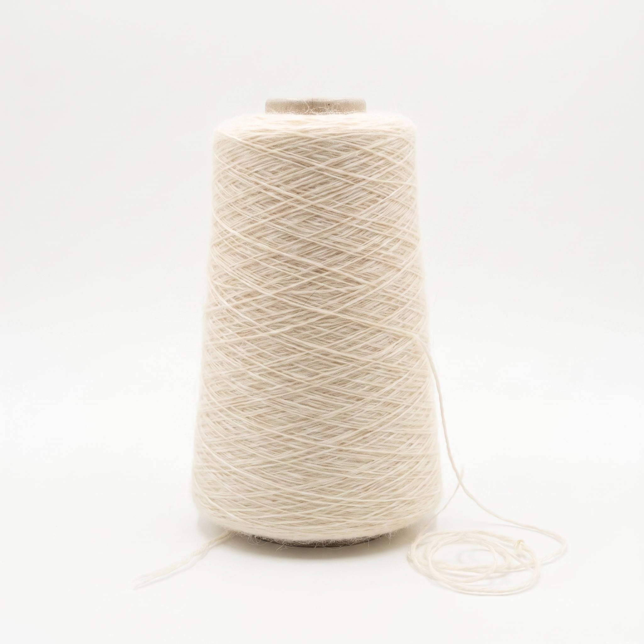 En cone med ljust beige, ulligt garn och en lös tråd vid basen.
