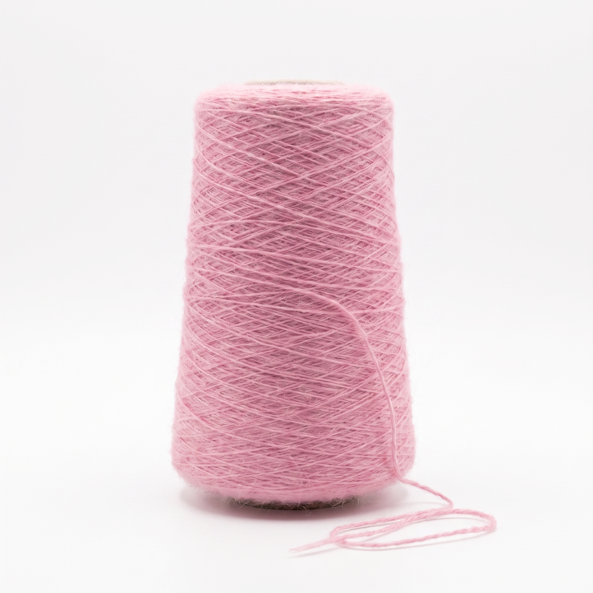 En stor cone med luddigt rosa garn och en lös tråd mot en vit bakgrund.