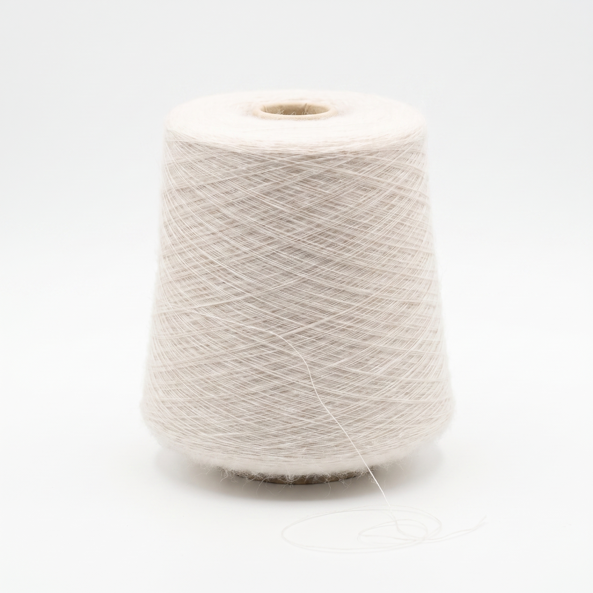 En cone av fint, ljust beige garn mot en vit bakgrund.