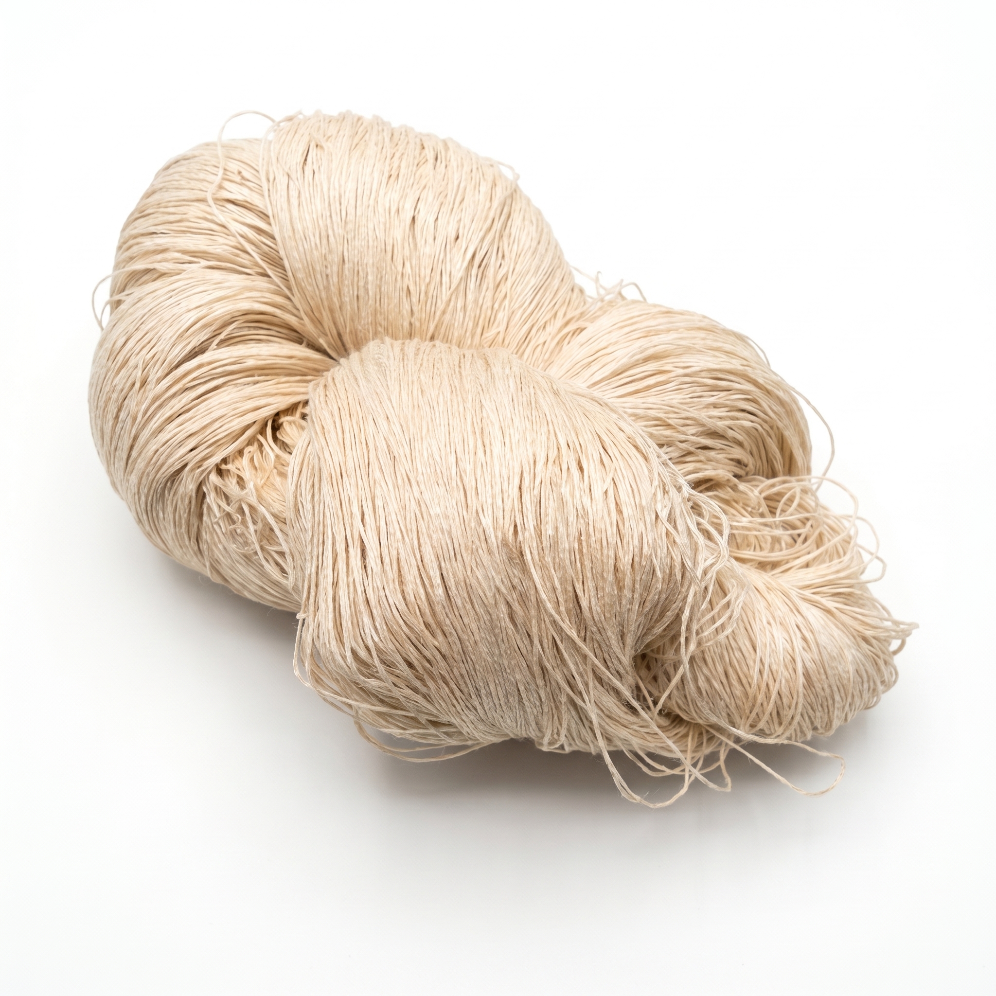 En stor härva av ljust beige garn ligger på en vit yta.
