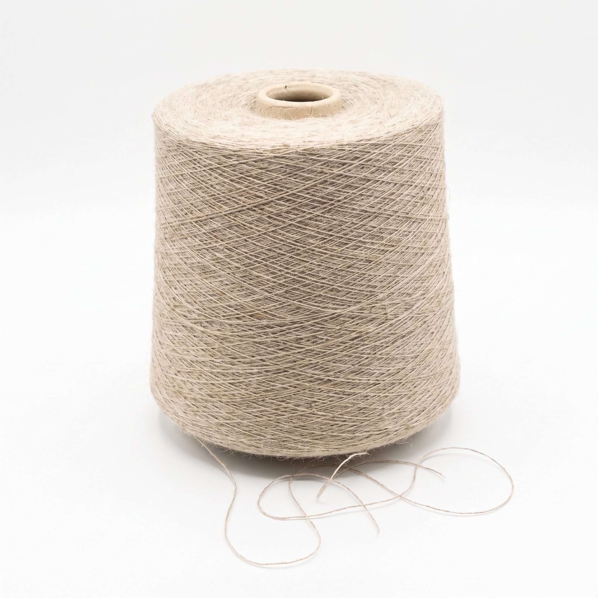 En stor cone av ljust beige garn visas på en vit yta, med lös tråd vid basen.