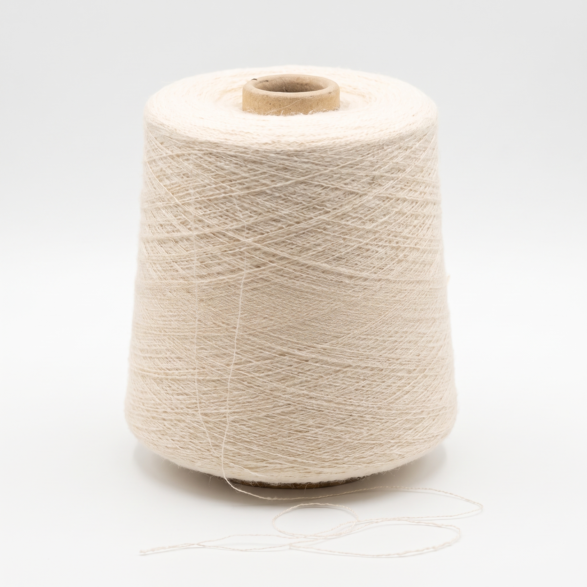 En stor cone med ljusbeige garn och en lös tråd.