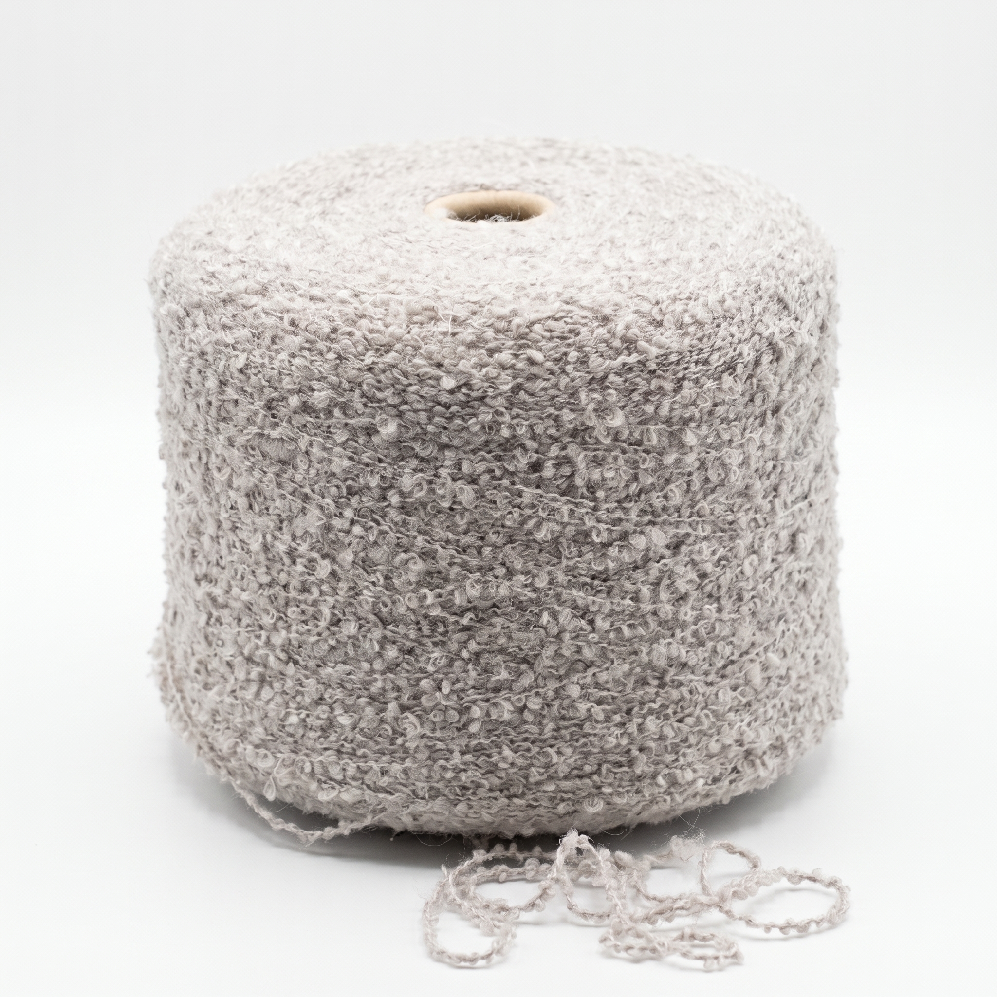 En stor cone med beige bouclé-garn och lite garn vid basen.