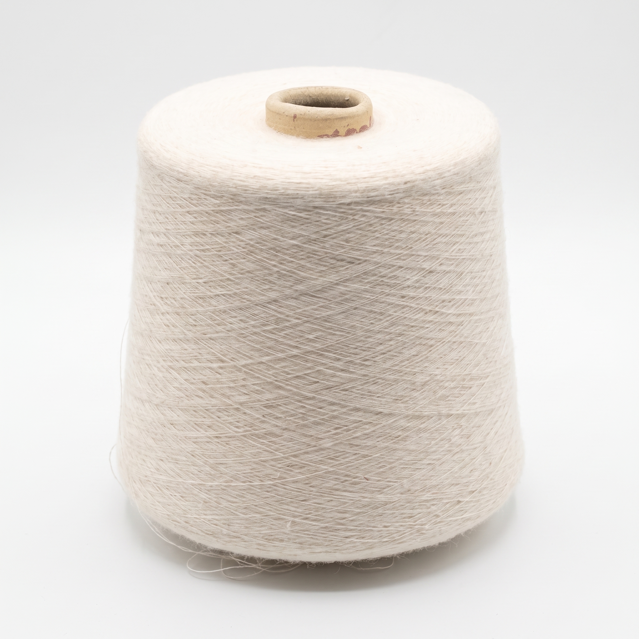 En cone med ljust beige garn på en vit bakgrund.