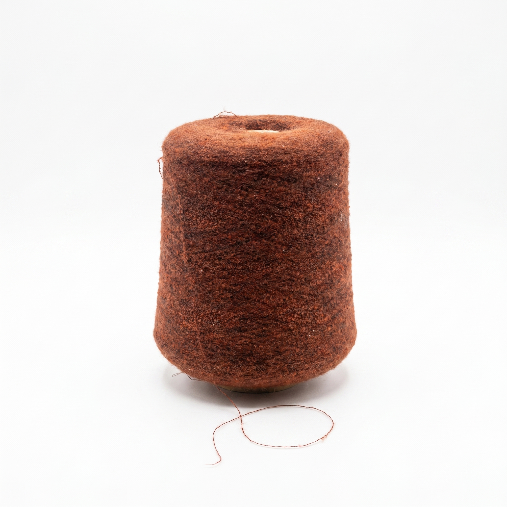 En stor cone med brunt, texturerat garn mot en vit bakgrund.
