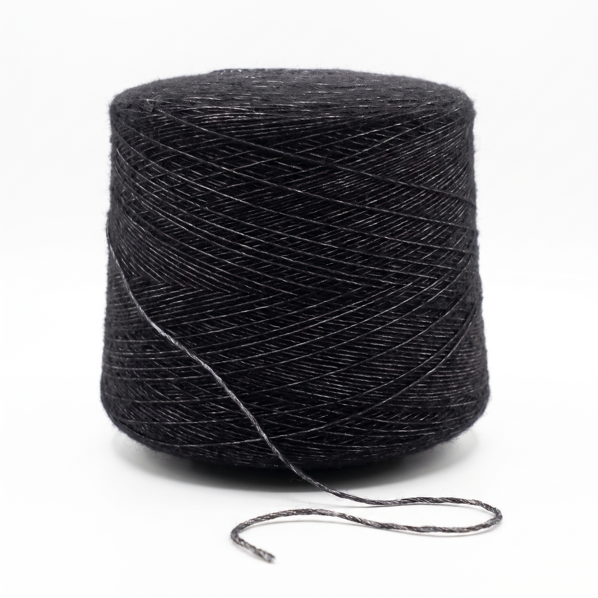 En cone av mörkgrått, texturerat garn med en lös trådände på en vit yta.