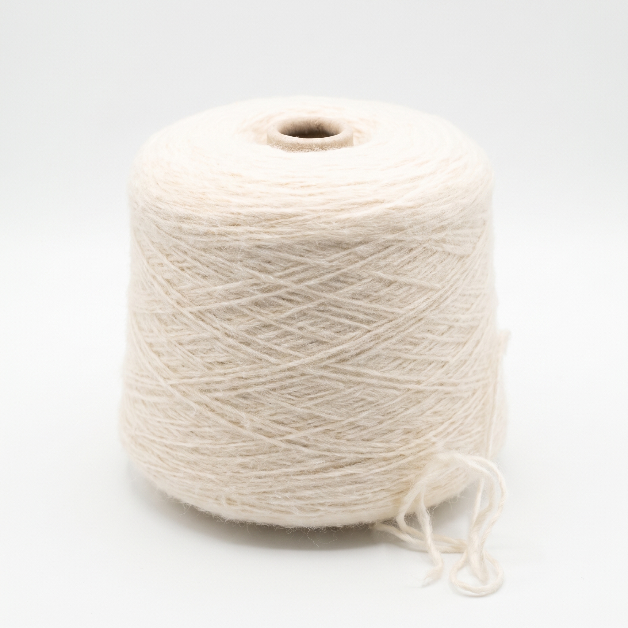 En cone med ljust beige garn på en vit bakgrund.