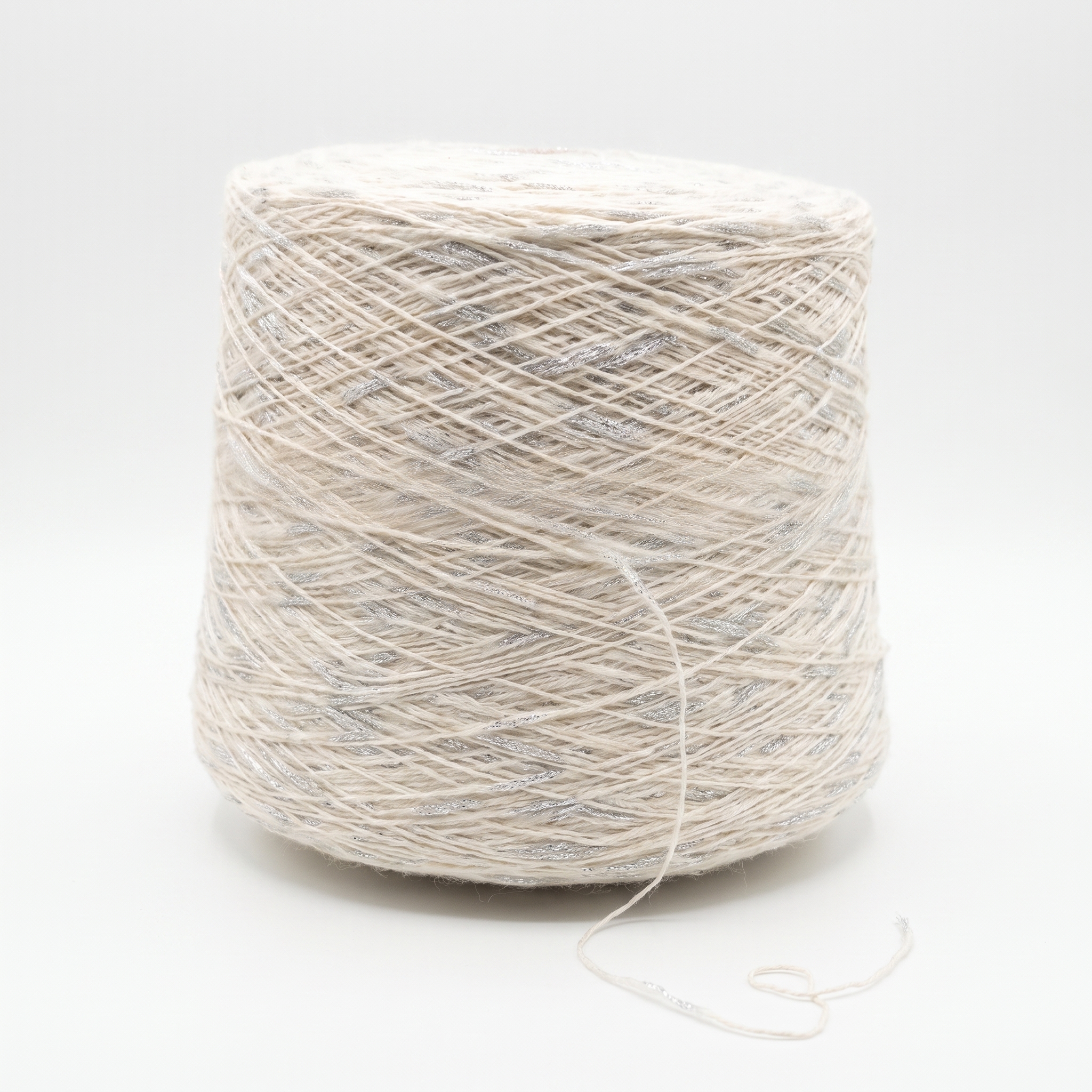 En stor cone med ljust beige garn och silverglittrande trådar, på en vit bakgrund.