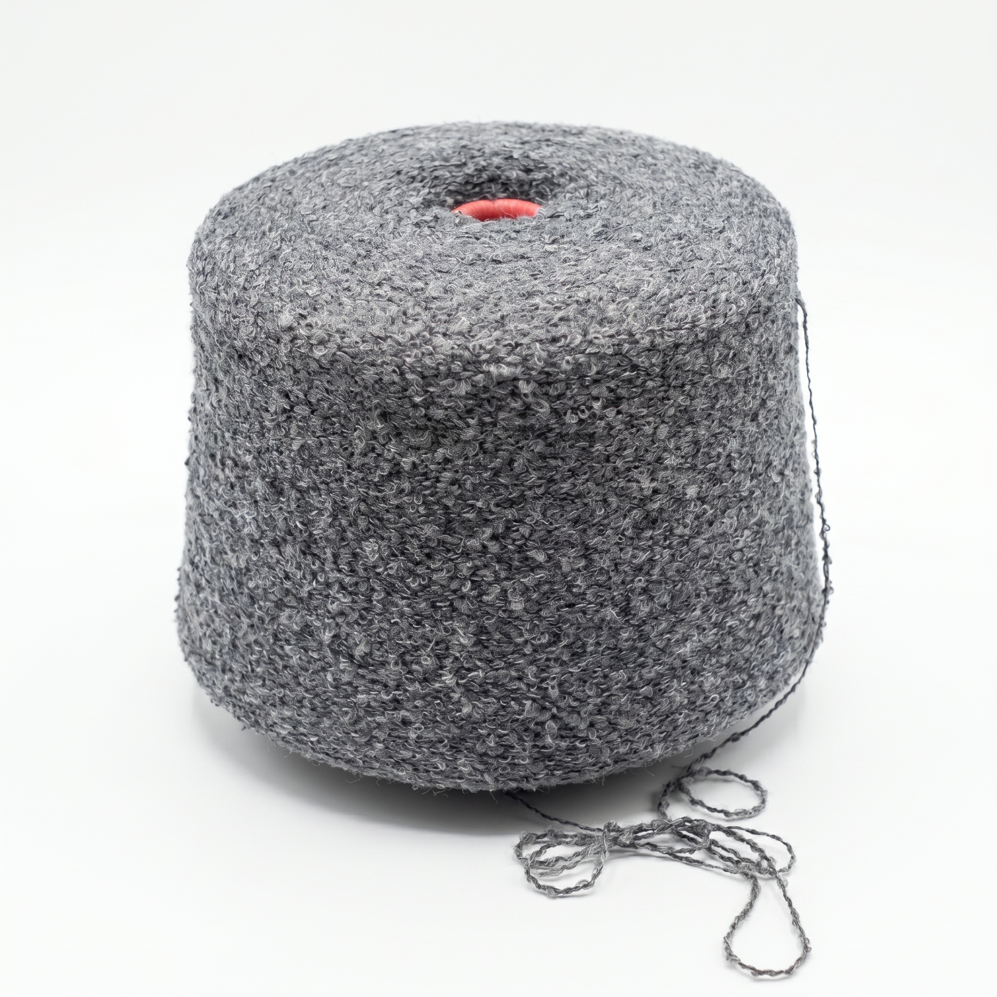 Grått bouclégarn på en cone med röd topp, mot en vit bakgrund.