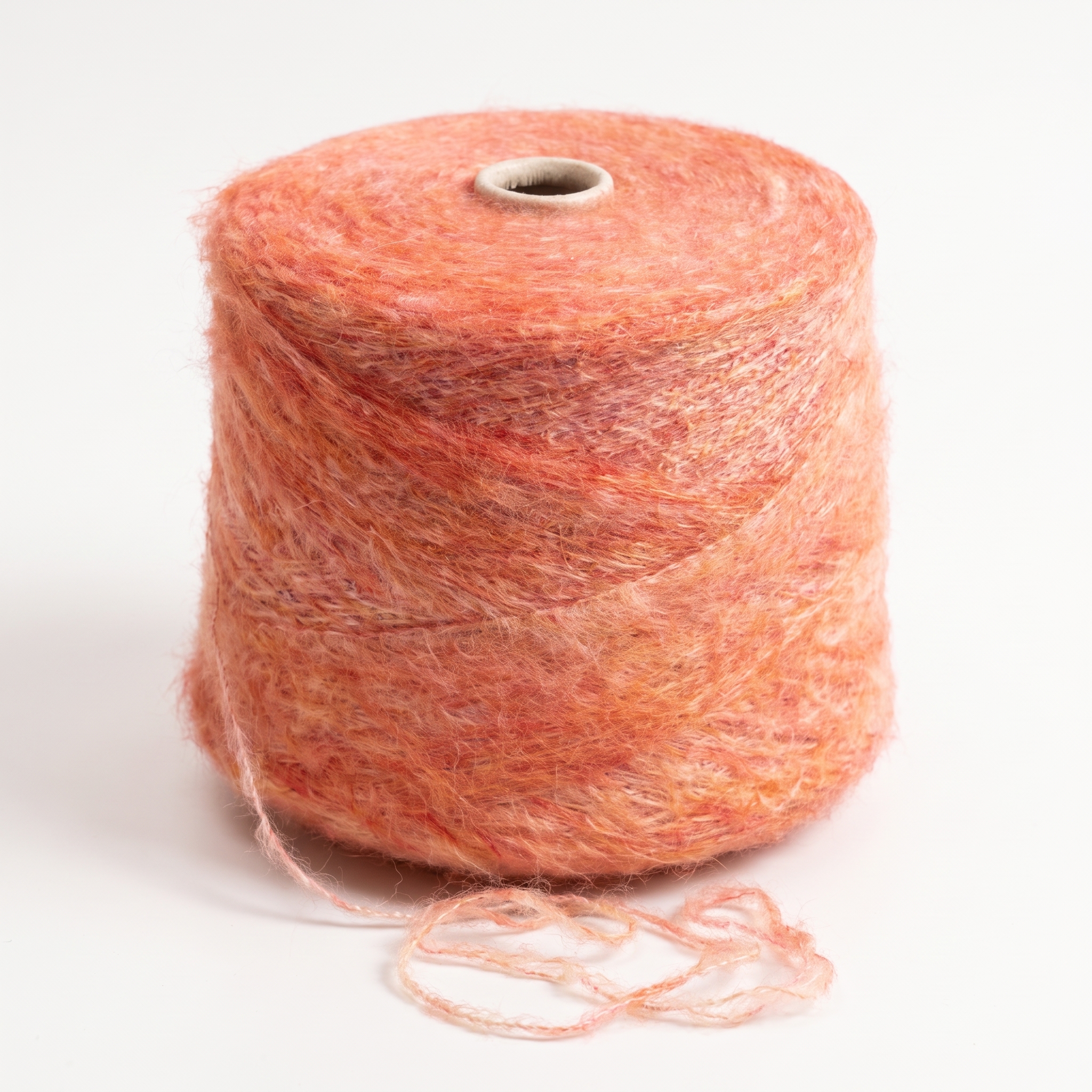 En cone med luddigt, flertonat orange garn på en vit bakgrund.