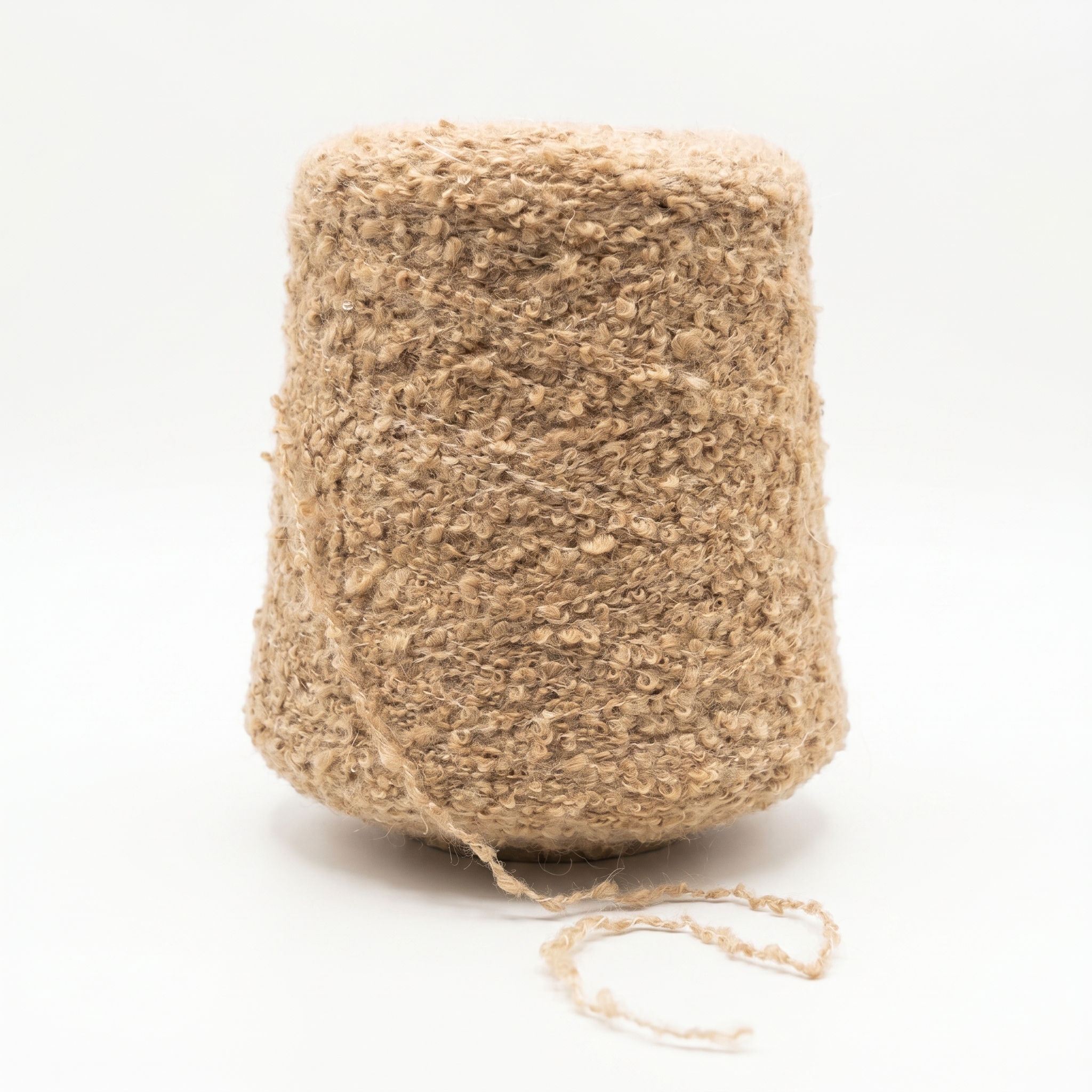 En stor cone med beige bouclégarn mot en vit bakgrund.