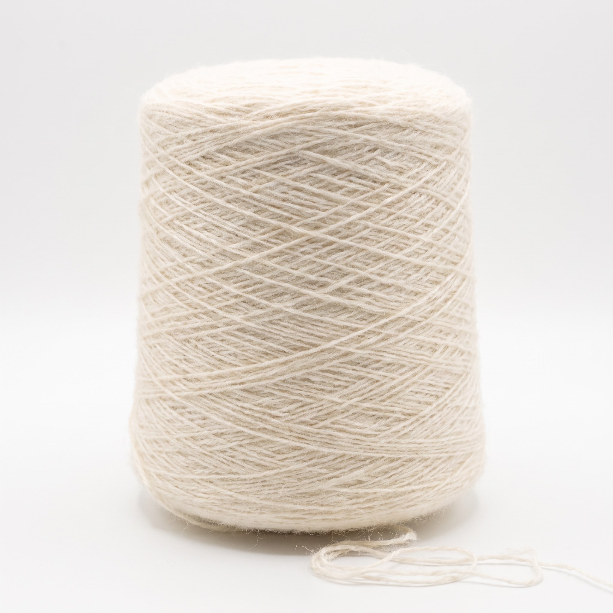 En stor cone av lyst beige garn, med en liten trådände som ligger löst vid botten.
