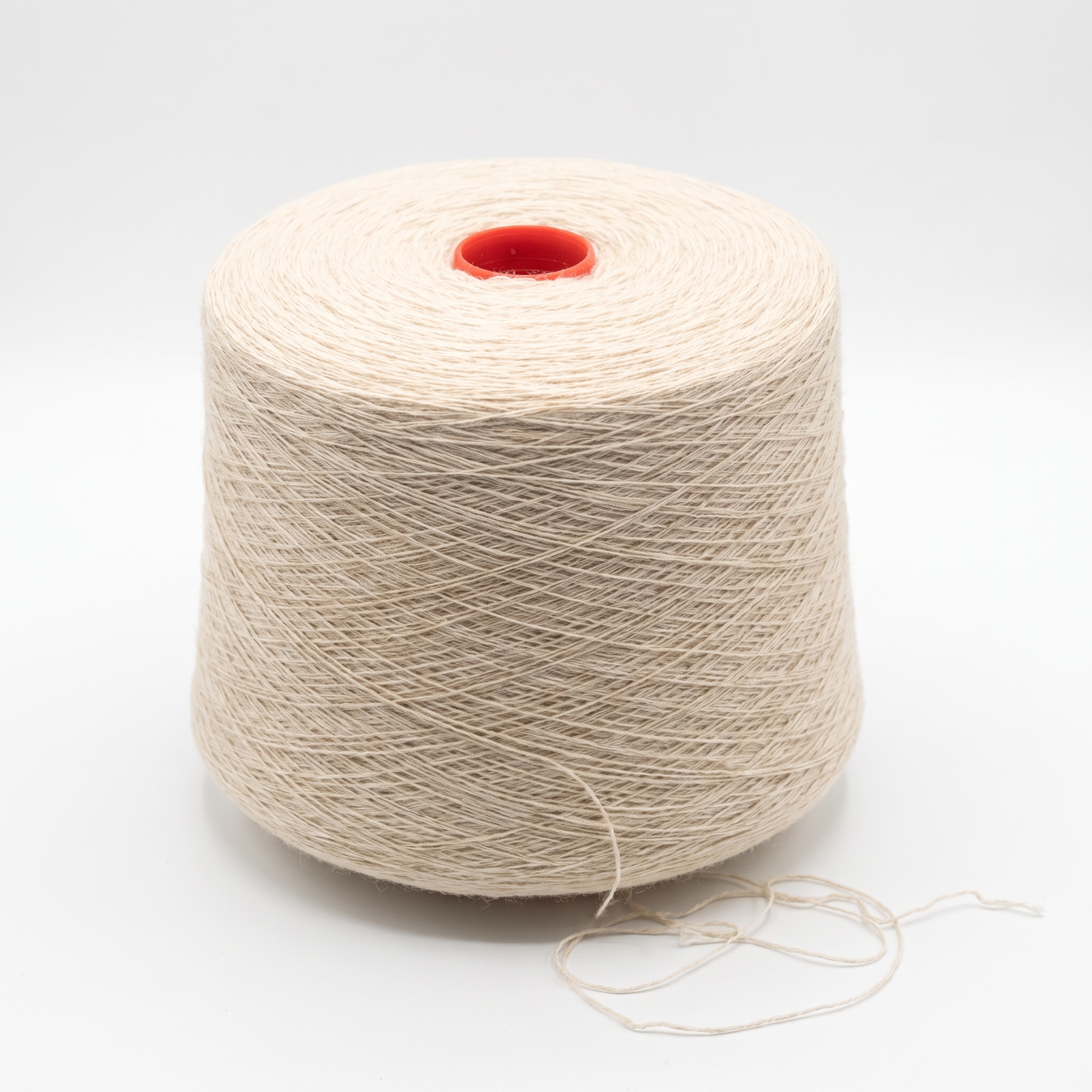 En stor cone med ljusbeige garn står på en vit yta.